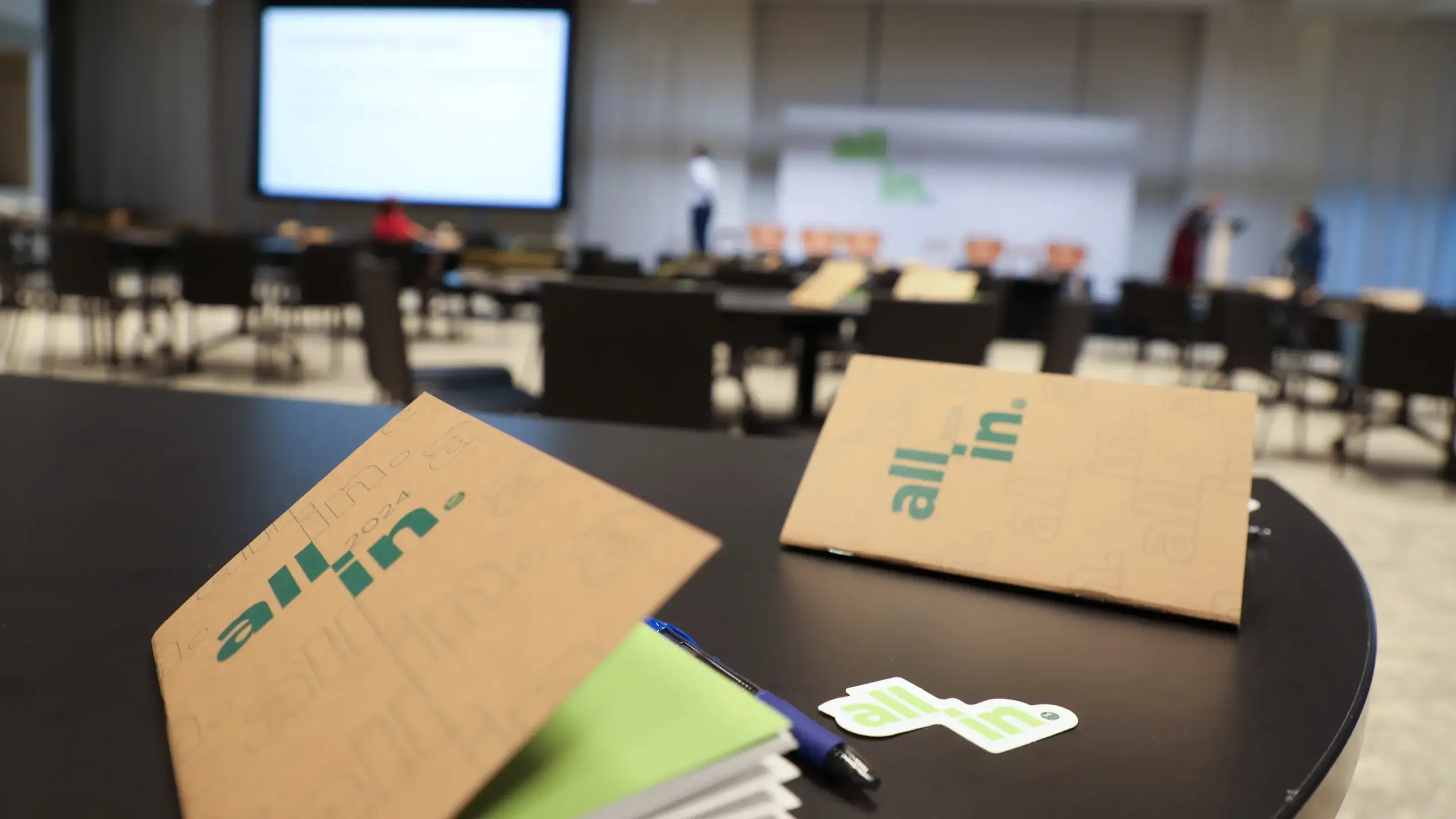 Printed brochures on a table in the the All In 2024 Summit room
