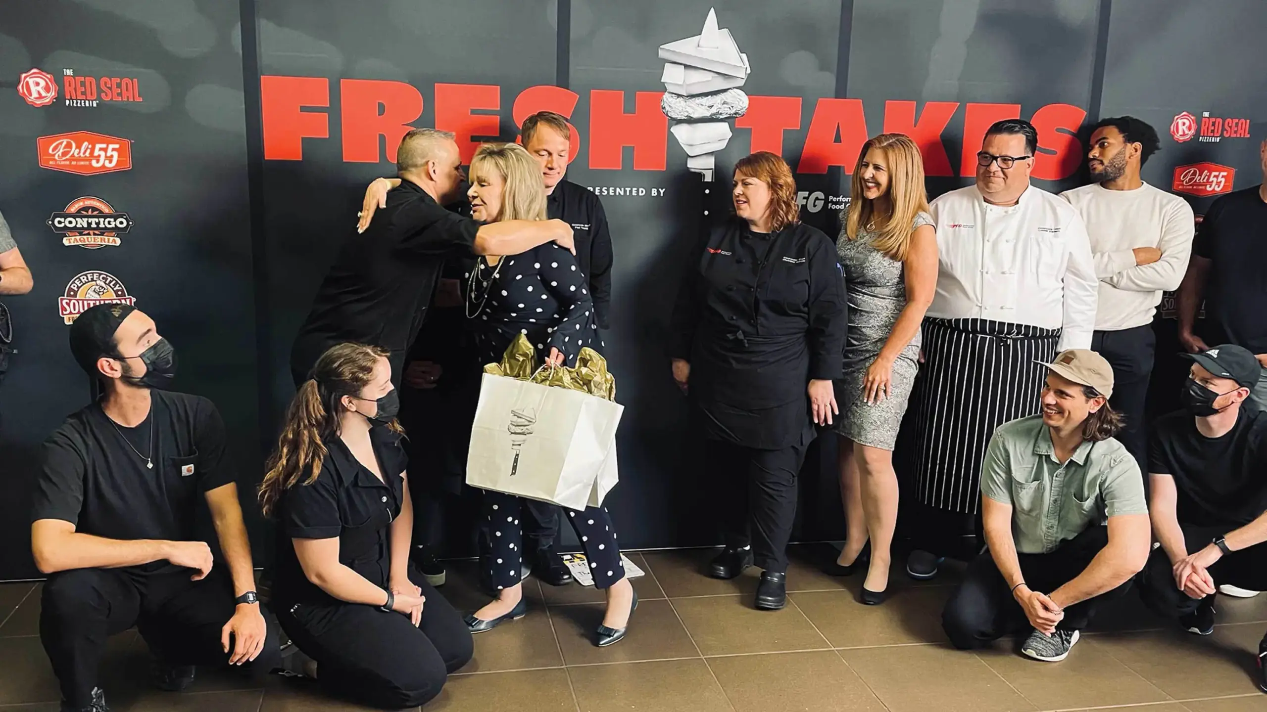 The full crew posing in front of the backdrop with FreshTakes by Performance Food Group branding