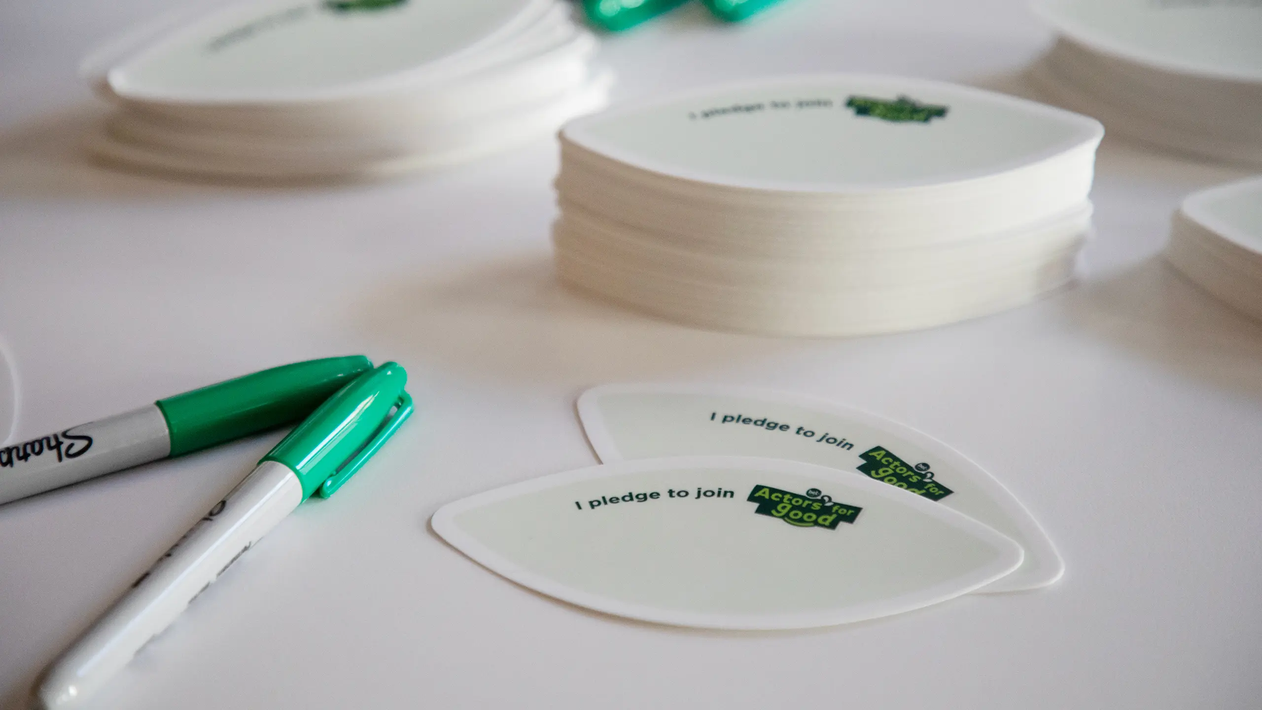Stickers in the shape of a leaf to adhere to the cardboard trees with markers on a table at the ‘All In 2025’