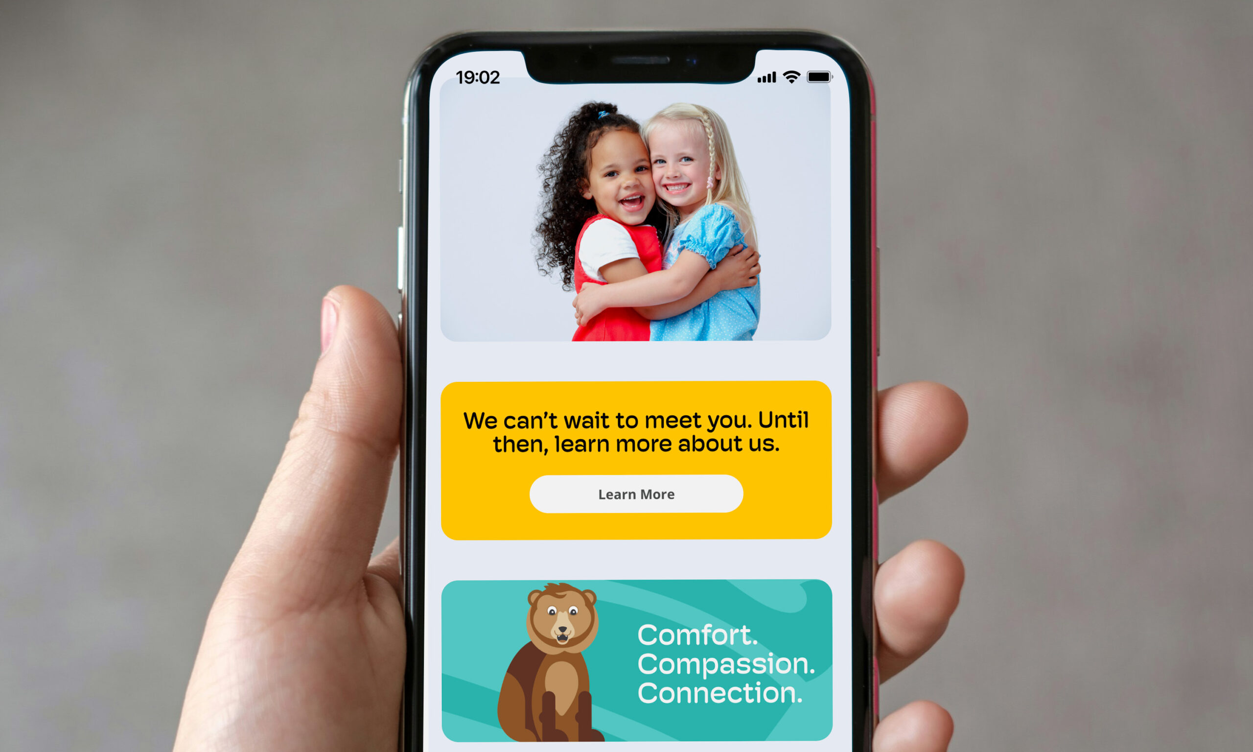 A hand holding a phone showing the homepage of the Blue Valley Pediatric Dentistry website