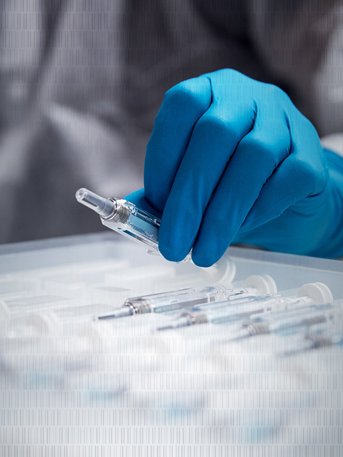 A gloved hand carefully handles a syringe from a sterile tray, evoking a sense of precision and clinical focus in a medical setting.